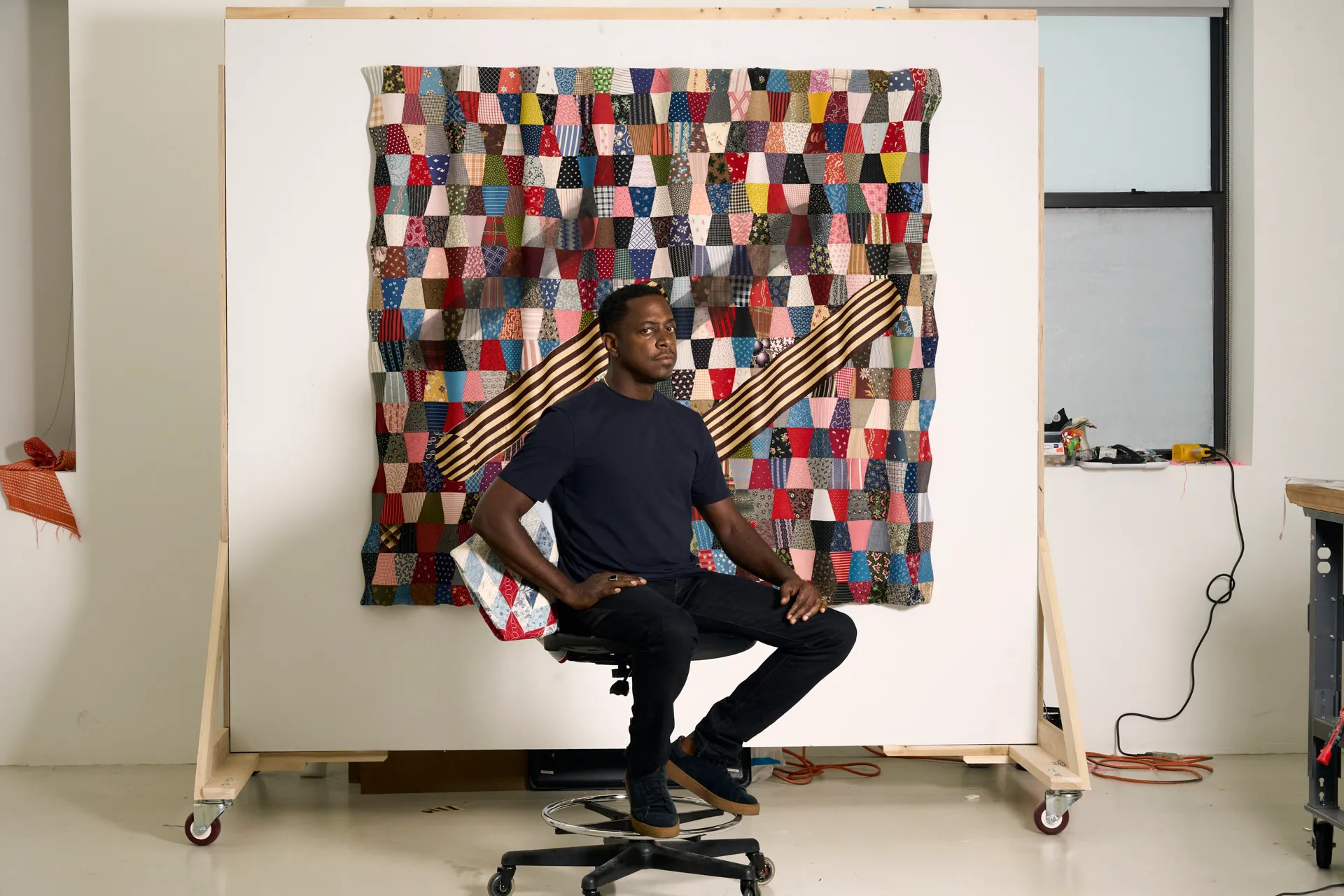 Portrait of Sanford Biggers in front of one of his artworks.