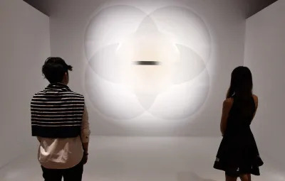 Two people looking at a work composed of multiple circles with a line in its center.