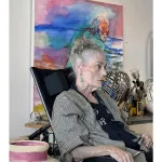 Portrait of Juanita McNeely, seated in front of a painting.