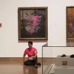 Kaleb Suedfeld sit in front of the Tom Thomson painting Northern River at the National Gallery of Canada. The On2Ottawa group member is wearing a bright pink shirt and reads from a piece of paper while his right hand is glued to the gallery