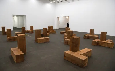 Unvarnished wood sculptures set within a gallery.