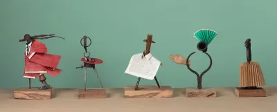 Five sculptures that appear to be maquettes for costumes, made from various metal instruments like a compass and pliers. 