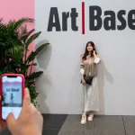 HONG KONG, CHINA - 2023/03/24: A visitor poses for a photo at the entrance of the Art Basel Hong Kong show after several years of remote and hybrid events due to covid restrictions in Hong Kong. (Photo by Sebastian Ng/SOPA Images/LightRocket via Getty Images)