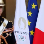 PARIS, FRANCE - FEBRUARY 26: The flag of the Paris 2024 Olympic Games is seen near the French national flag and the European flag at the entrance of the Elysee Palace during a conference in support of Ukraine with European leaders and government representatives on February 26, 2024 in Paris, France. February 24 marked two years since Russia