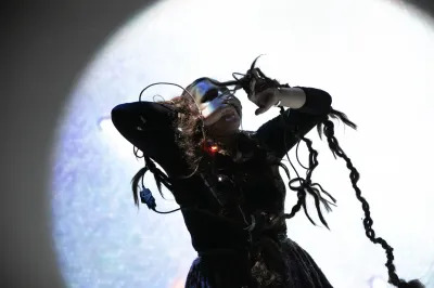 A woman performs with long hair braids that have sensors in them. 