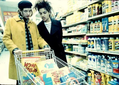 Two women with a shopping cart filled with cereal.