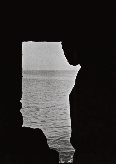 A photograph showing two figures in profile staring out at a sea.