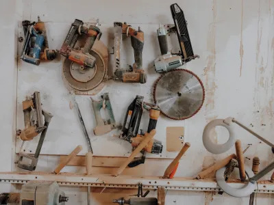 Various power saws and other fools hang on a wall in an organized fashion. 