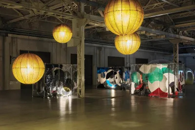 A room filled with box-like sculptures and hanging lamps.