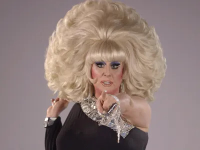 A drag queen, Lady Bunny, with a giant blonde wig pointing a finger at the viewer.