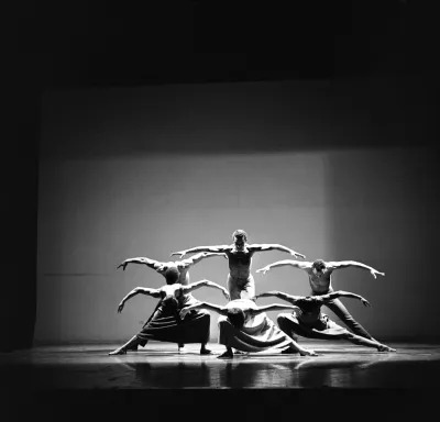 Archival photograph of a group of dancers with their arms outstretched. 