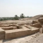 View of World Heritage site of Tell es-Sultan in the West Bank, which is mostly a ruin of a building in dirt with palm trees in the background.