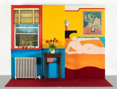 A painted nude white woman reclining on a couch. The image is situated in a replica of an apartment