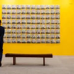 A man looks at an artwork on a wall.