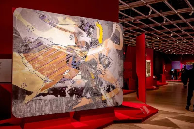 View of a museum exhibition with red walls and a large painting of Katherine Dunham dancing. 