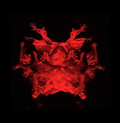 A photograph showing a bunch of hands, arms, and bodies, all of which are tinted red.