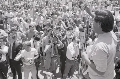 (Original Caption) 7/25/1970-San Rafael, CA- Cesar Chavez, director of the United Farm Workers Organizing Committee, gives victory sign to over one thousand members of various Northern California unions who staged a peaceful march against the San Rafael independent-Journal in support of the Typographical Union which has been on strike against the Bay Area newspaper for six months. Chavez addressed the crowd during rally at Albert Park and called for a non-violent boycott of the paper.