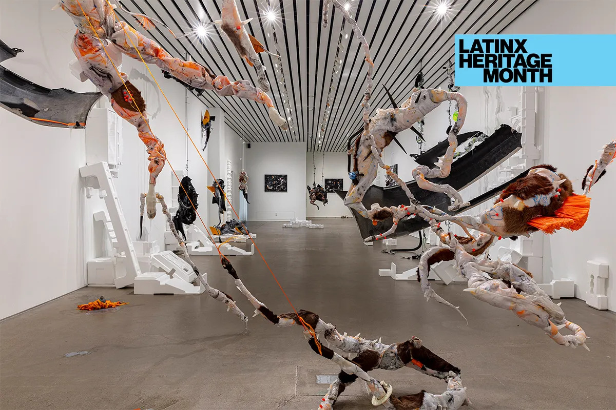 A gallery with tangles of orange objects and styrofoam pieces. Above the image is a badge reading 