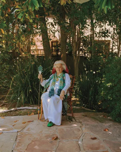 Joan Quinn shits in a wooden chair in her home