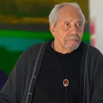 Portrait of Richard Mayhew, standing in front of one of his abstract paintings.