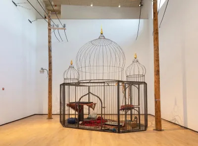 A Taj Mahal–shaped caged featuring drones covered by carpets. 