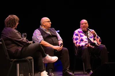 Three people sitting on a stage with microphones.