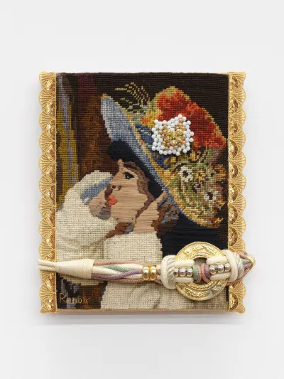 A vintage needlepoint reproduction of a Renoir painting of a girl wearing a brimmed hat covered in flowers. White and gold beads in the shape of a flower are sewn onto the hat. A corded belt with a gold buckle is affixed across the lower part of the needlepoint.