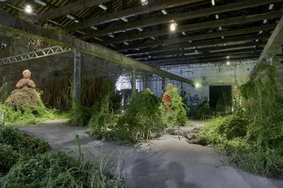 An installation featuring overflowing greenery and a female figure made of dirt.