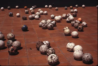 Groupings of tattered soccer balls on a tiled floor.