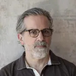 A white man in glasses with graying hair and beard.