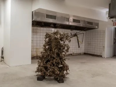 A large bronze sculpture in a barren former restaurant kitchen.