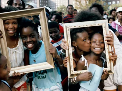 Two pairs of Black children holding picture frames before their faces.