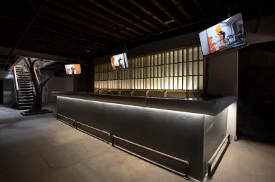 A former restaurant bar with three TVs showing a video work.