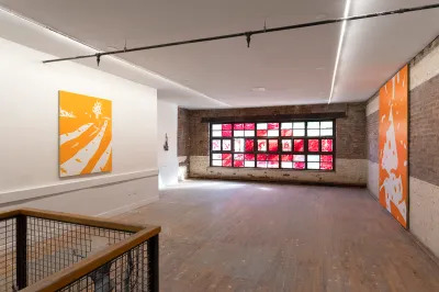 A large empty room with two paintings and sort of stained-glass window.