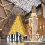 A large atrium dominated by a tall Egyptian statue and a triangular entryway.