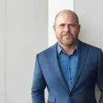 A man in a blue blazer and blue collared shirt.