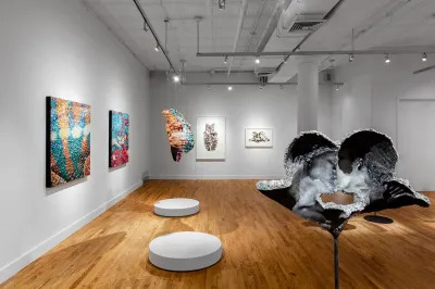 View of a museum exhibition with sculptures, paintings, and body prints on view. 