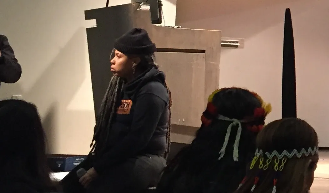 A woman in a beanie sitting on a stage.