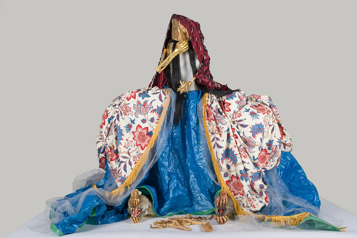 A sculpture resembling a person whose dress is split open to reveal tarp and animals