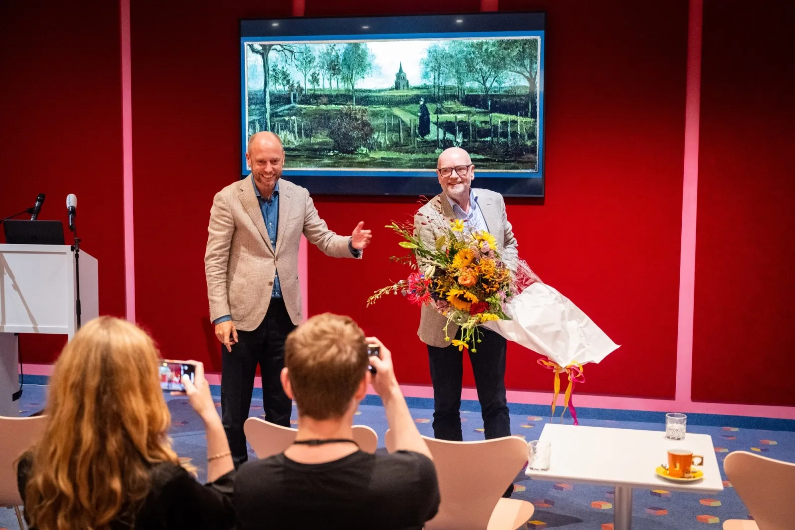 A man receives flowers in front of a recovered Van Gogh painting.