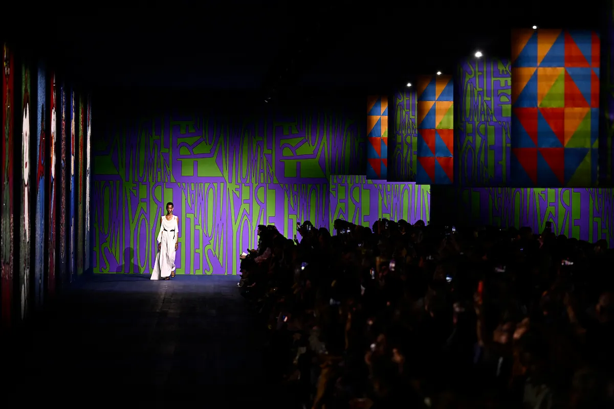 A model walking a runway with the repeated words 