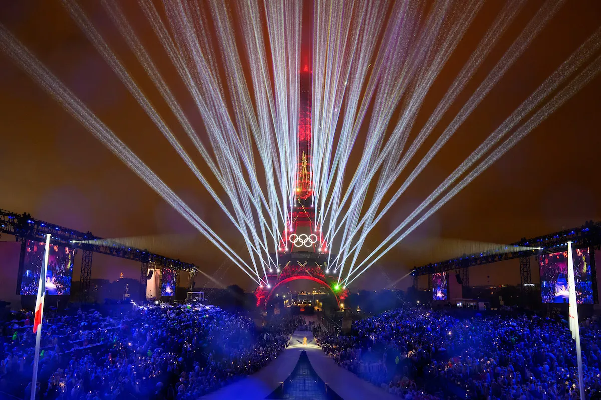 The Eiffel Tower with red with white laser-like lights streaming out from behind it.