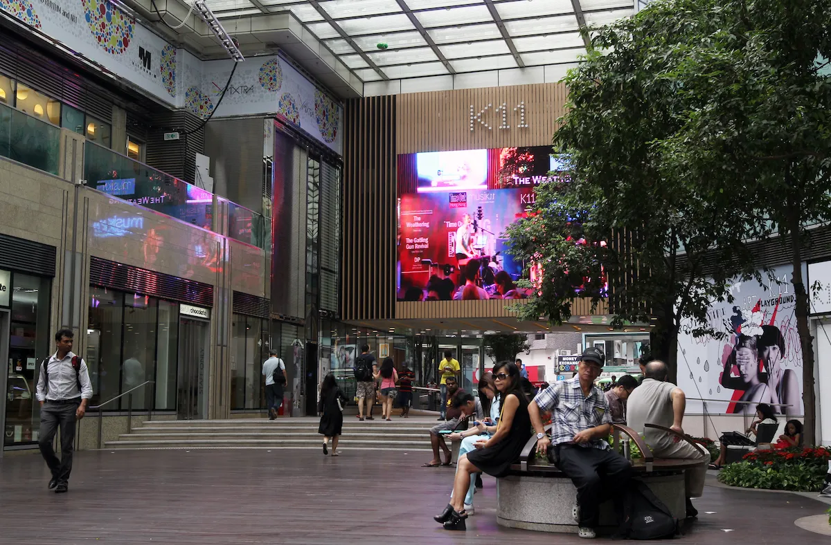 A mall atrium with people sitting on benches and walking on a staircase.