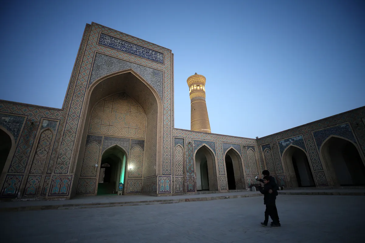 Two people standing before the entrance to a madrasa.