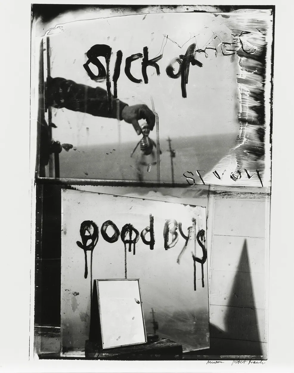 Two stacked vintage photos in bad shape. The top one shows a hand in the foreground squeezing a head in the background. The bottom is a picture of a mirror. Wet text is written over the pictures and says "sick of goodby